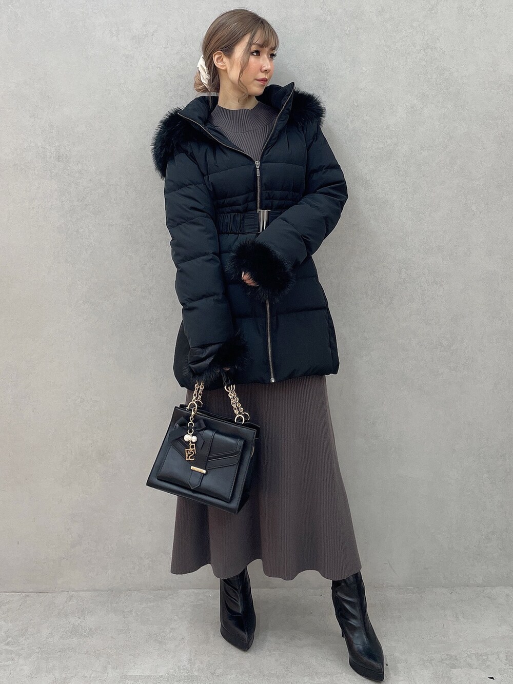 グレー系のワンピース、ブラック系のハンドバッグ、ブラック系のブーツを着用したレディースの秋コーディネートの2枚目の写真