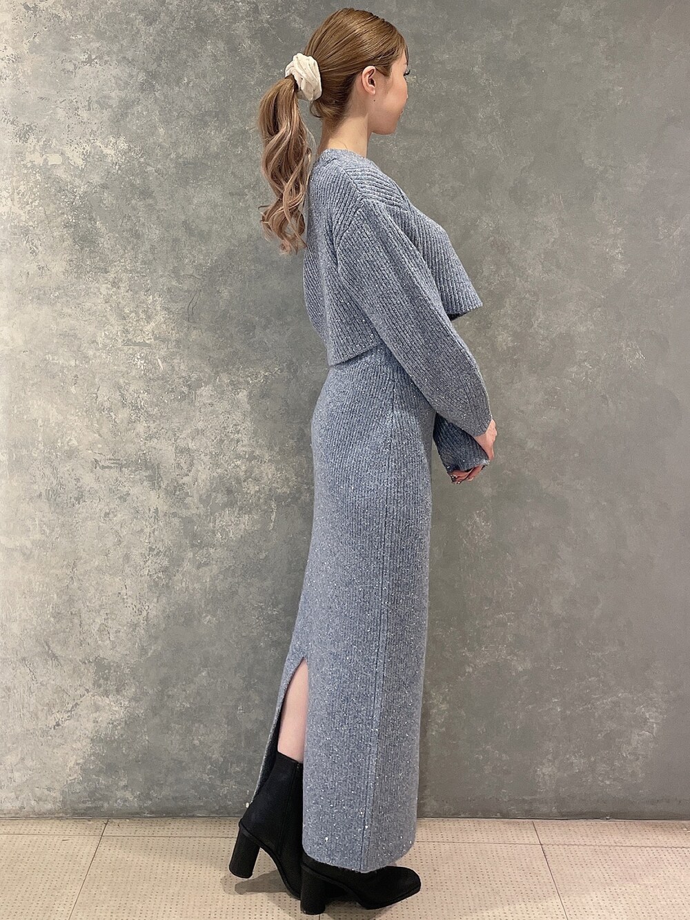 ブルー系のニット/セーター、ブルー系のスカート、ブラック系のブーツを着用したレディースの秋コーディネートの3枚目の写真