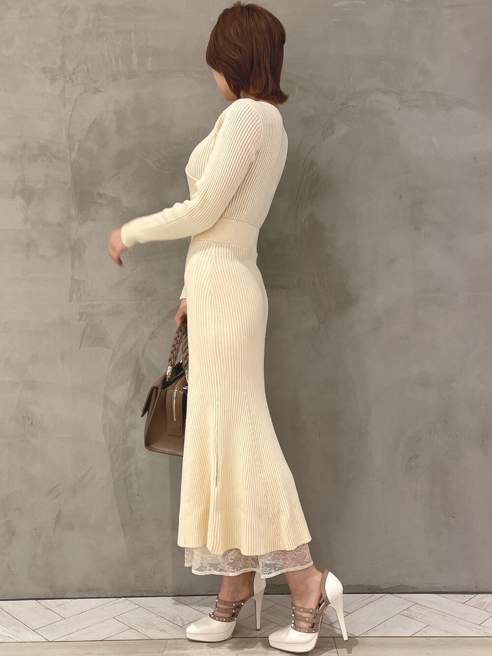 ホワイト系のワンピース、ホワイト系のパンプス、ブラウン系のハンドバッグを着用したレディースの秋コーディネートの3枚目の写真