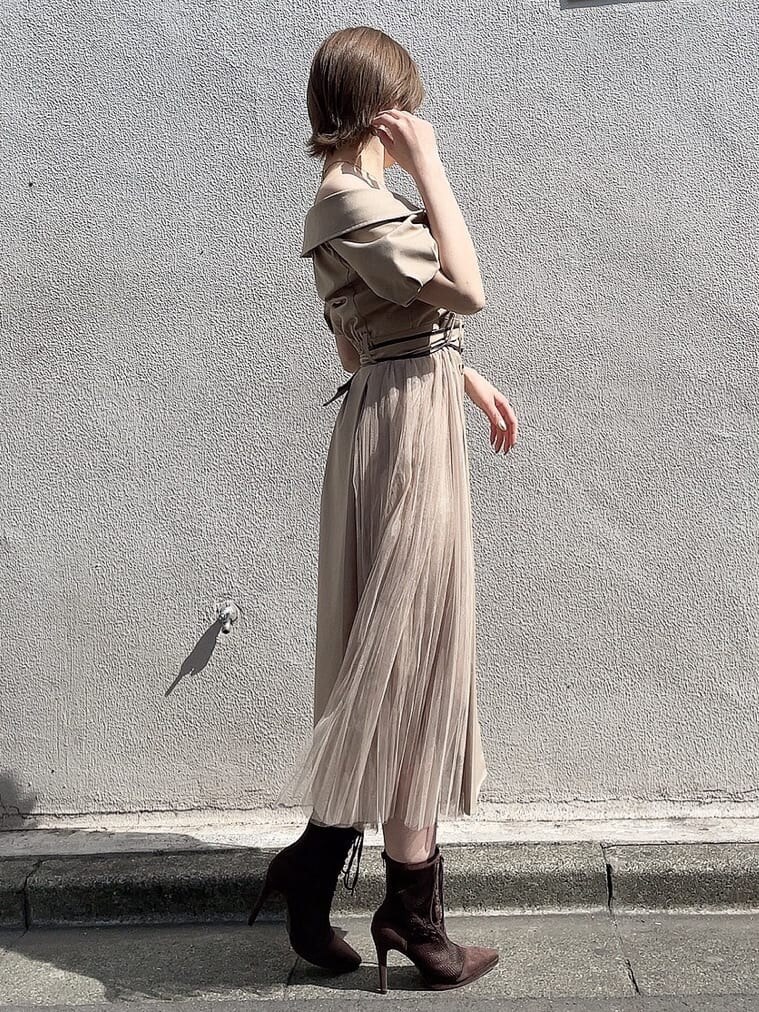 ベージュ系のワンピース、ブラウン系のブーツ、ゴールド系のネックレスを着用したレディースの春コーディネートの2枚目の写真