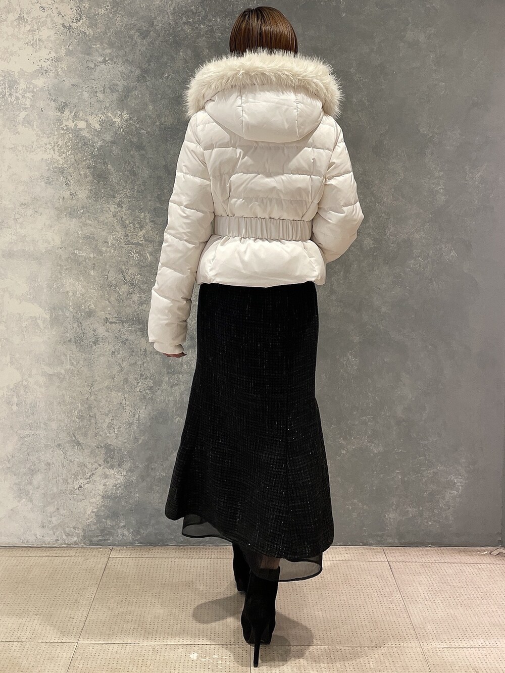 ホワイト系のダウンジャケット/コート、ブラック系のスカート、ブラック系のブーツを着用したレディースの秋コーディネートの3枚目の写真