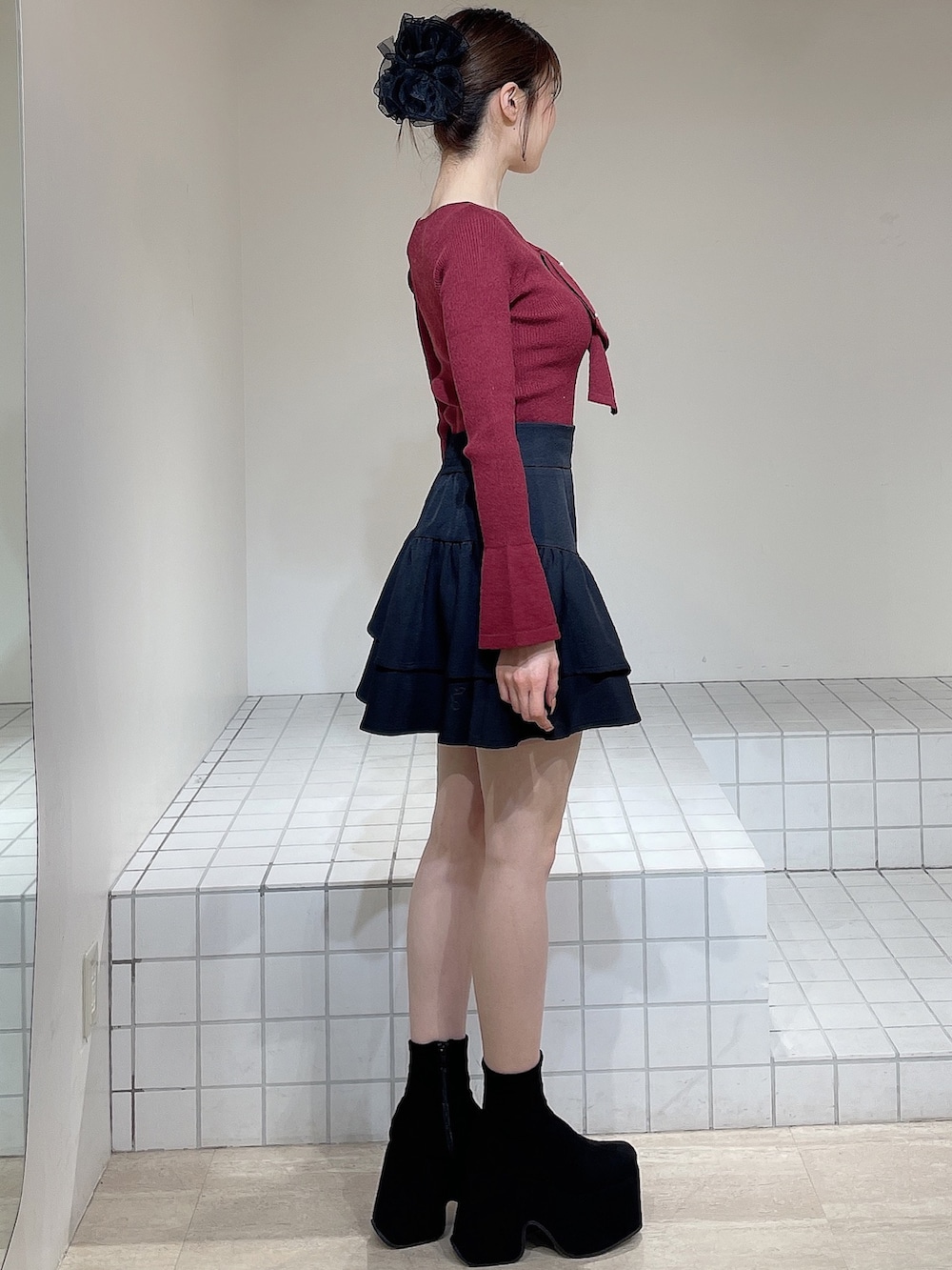 レッド系のニット/セーター、ブラック系のスカート、ブラック系のブーツを着用したレディースの冬コーディネートの3枚目の写真