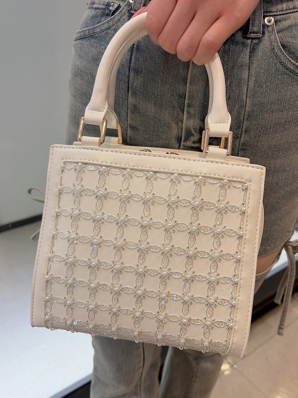ホワイト系のニット/セーター、ブルー系のデニムパンツ、ホワイト系のハンドバッグを着用したレディースの夏コーディネートの7枚目の写真
