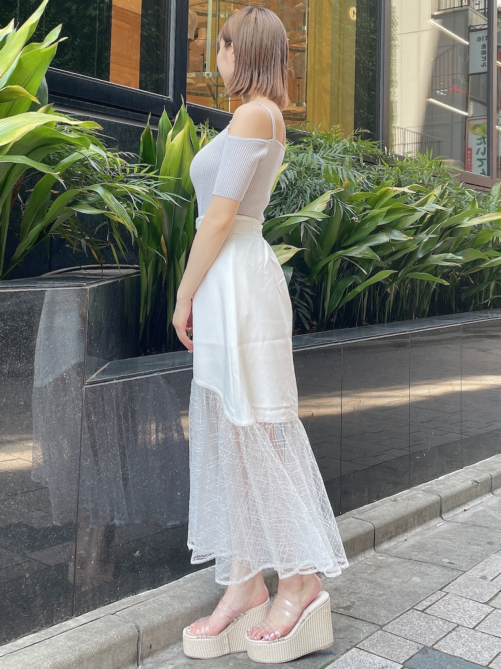 グレー系のニット/セーター、ホワイト系のスカート、ホワイト系のサンダルを着用したレディースの夏コーディネートの3枚目の写真