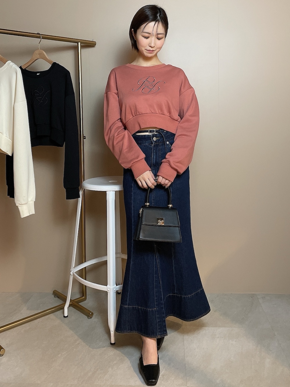 ブラック系のハンドバッグ、オレンジ系のスウェット、ブルー系のデニムスカートを着用したレディースの冬コーディネートの2枚目の写真