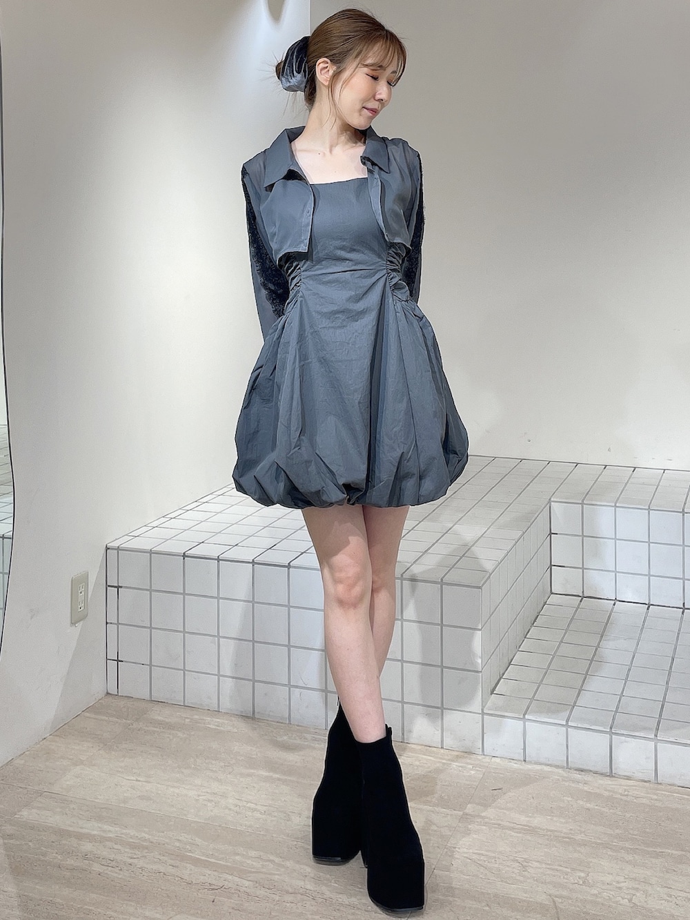 グレー系のワンピース、ブラック系のブーツ、グレー系のシュシュを着用したレディースの秋コーディネートの2枚目の写真