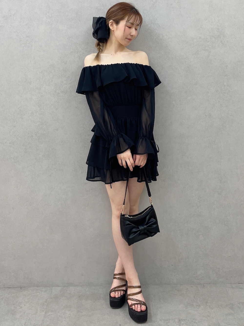 ブラック系のワンピース、ブラック系のハンドバッグ、ブラック系のサンダルを着用したレディースの春コーディネートの2枚目の写真