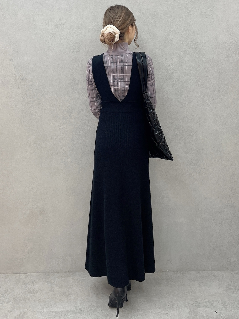 パープル系のニット/セーター、ブラック系のブーツ、ブラック系のジャンパースカートを着用したレディースの秋コーディネートの4枚目の写真