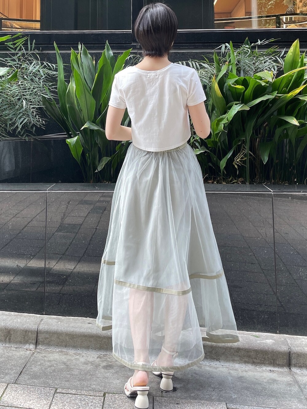 グリーン系のスカート、ホワイト系のサンダル、ホワイト系のTシャツ/カットソーを着用したレディースの春コーディネートの4枚目の写真