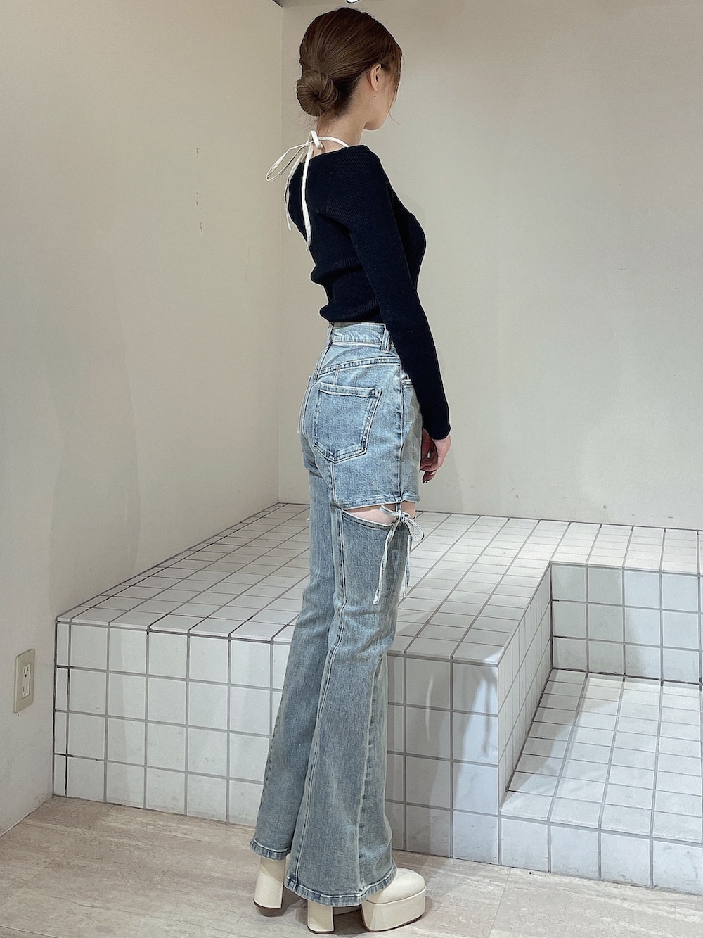 ブラック系のニット/セーター、ブルー系のデニムパンツ、ホワイト系のブーツを着用したレディースの冬コーディネートの3枚目の写真