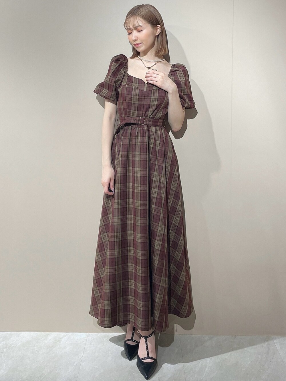 レッド系のワンピース、ブラック系のパンプス、ゴールド系のネックレスを着用したレディースの夏コーディネートの2枚目の写真