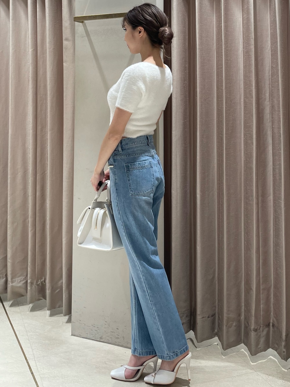 ホワイト系のハンドバッグ、ホワイト系のニット/セーター、ブルー系のデニムパンツを着用したレディースの夏コーディネートの2枚目の写真