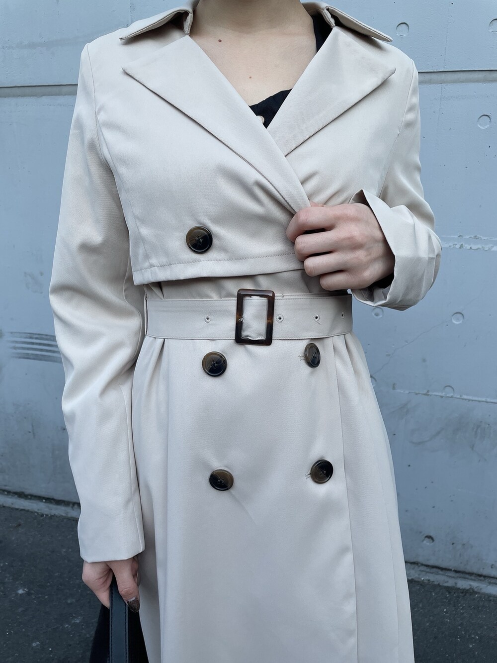 ベージュ系のトレンチコート、ブラック系のワンピース、ブラック系のハンドバッグを着用したレディースの冬コーディネートの8枚目の写真