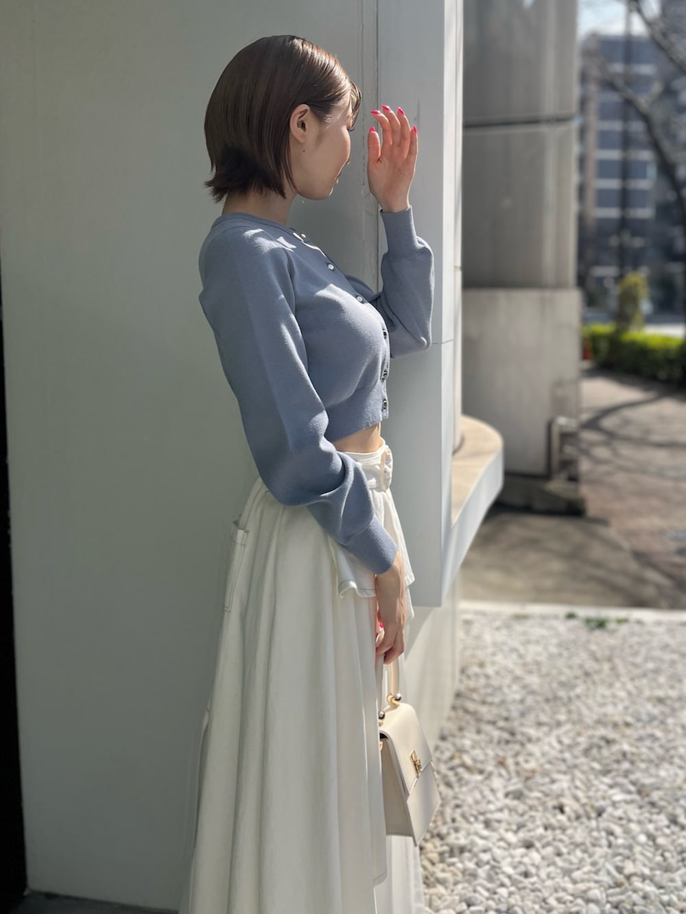 ブルー系のカーディガン/ボレロ、ホワイト系のデニムスカート、ホワイト系のハンドバッグを着用したレディースの春コーディネートの4枚目の写真
