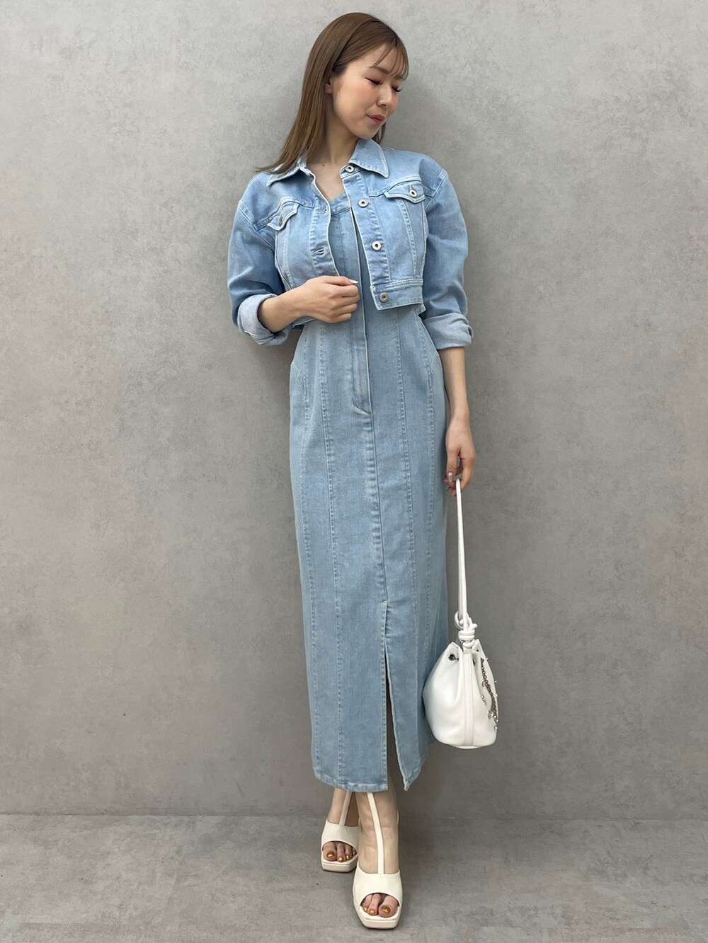 ブルー系のデニムジャケット、ブルー系のワンピース、ホワイト系のハンドバッグを着用したレディースの春コーディネートの2枚目の写真