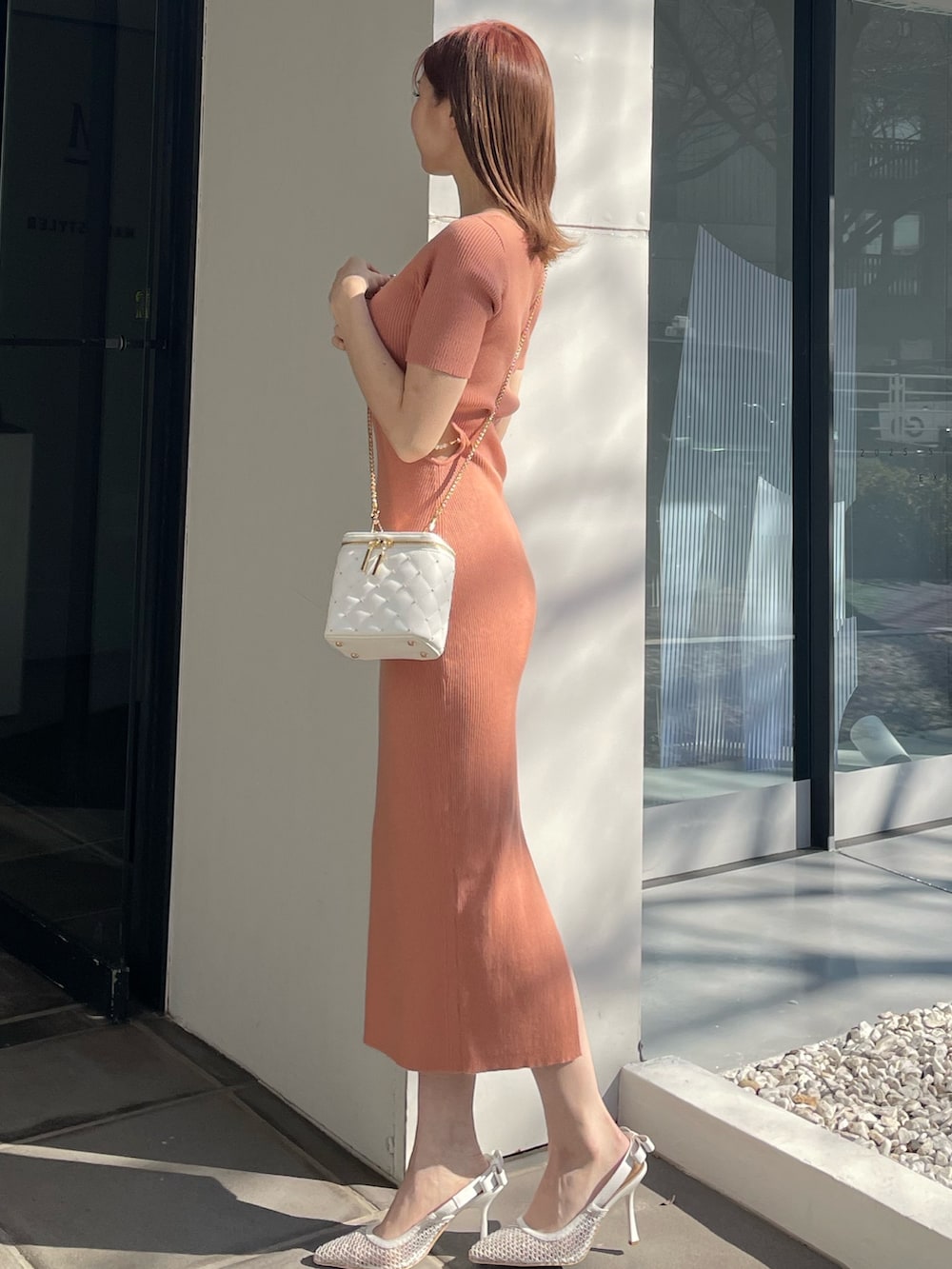 オレンジ系のワンピース、ホワイト系のショルダーバッグ、ホワイト系のパンプスを着用したレディースの冬コーディネートの2枚目の写真