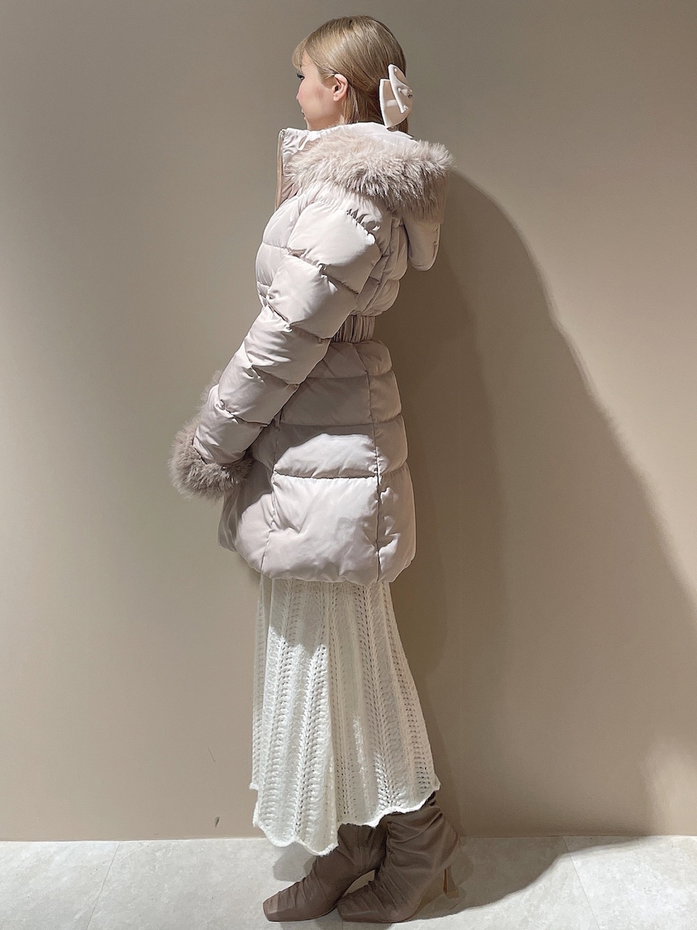 ベージュ系のブーツ、ベージュ系のダウンジャケット/コート、ホワイト系のワンピースを着用したレディースの秋コーディネートの5枚目の写真