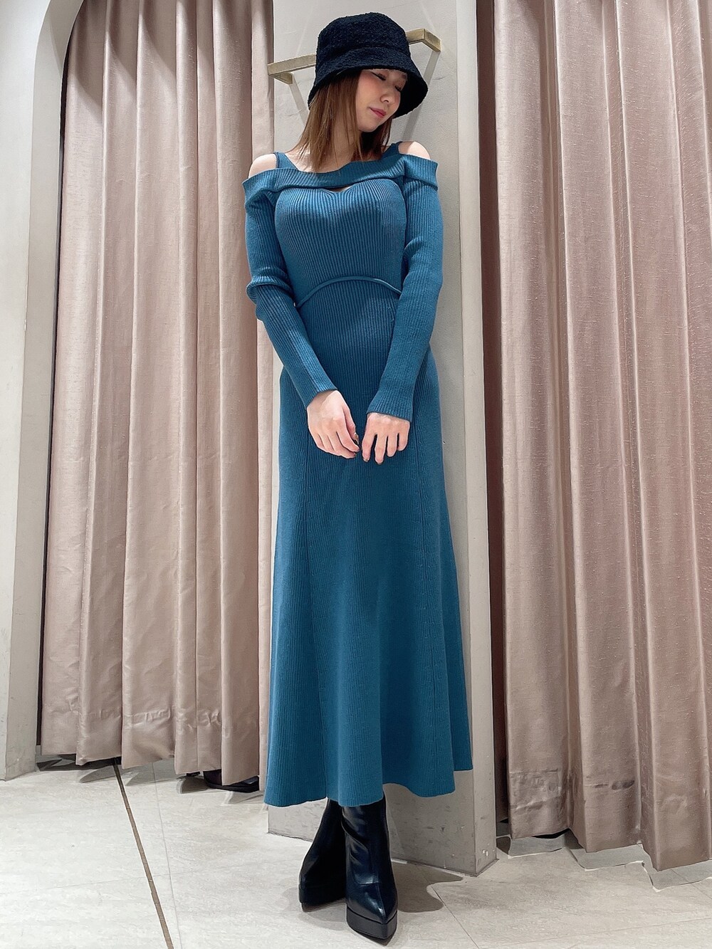 ブルー系のワンピース、ブラック系のブーツ、ブラック系のハットを着用したレディースの冬コーディネートの2枚目の写真