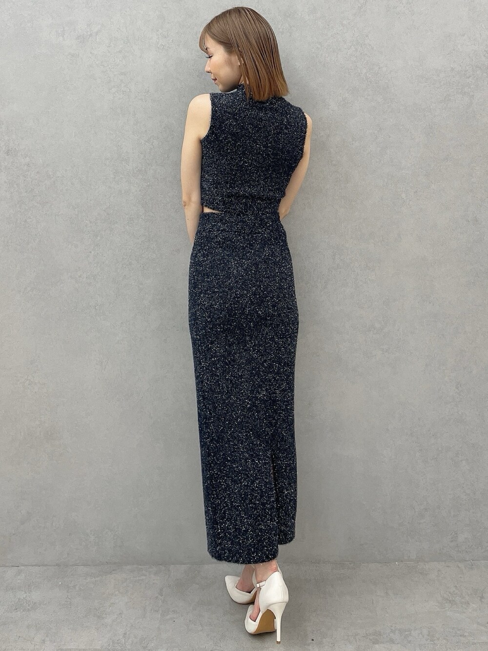 ブラック系のニット/セーター、ブラック系のスカート、ホワイト系のパンプスを着用したレディースの夏コーディネートの4枚目の写真