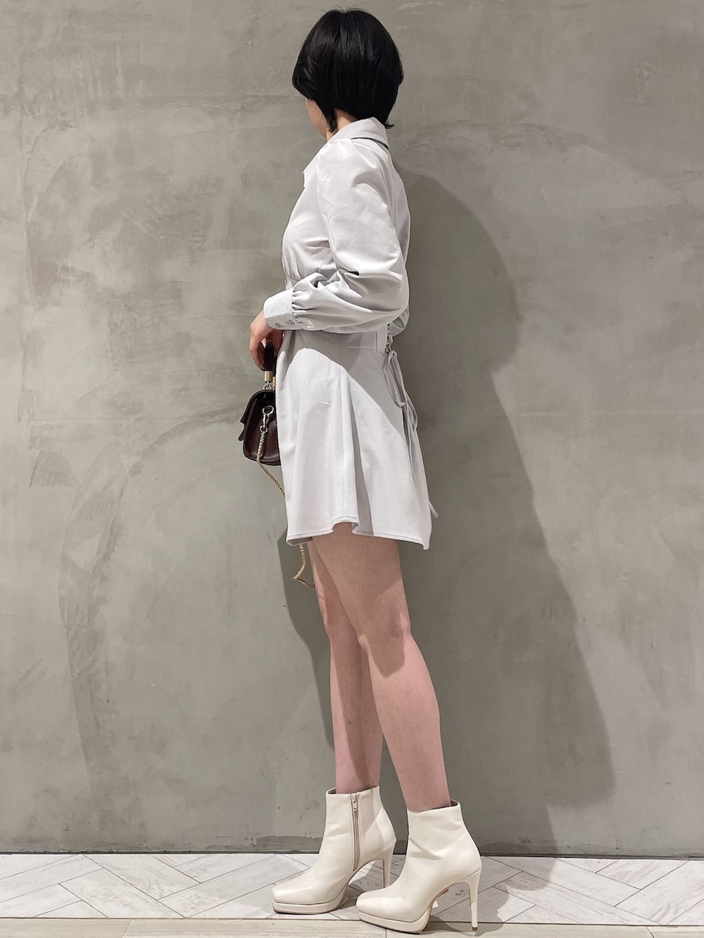 ブラウン系のハンドバッグ、ホワイト系のブーツ、グレー系のシャツワンピースを着用したレディースの冬コーディネートの2枚目の写真