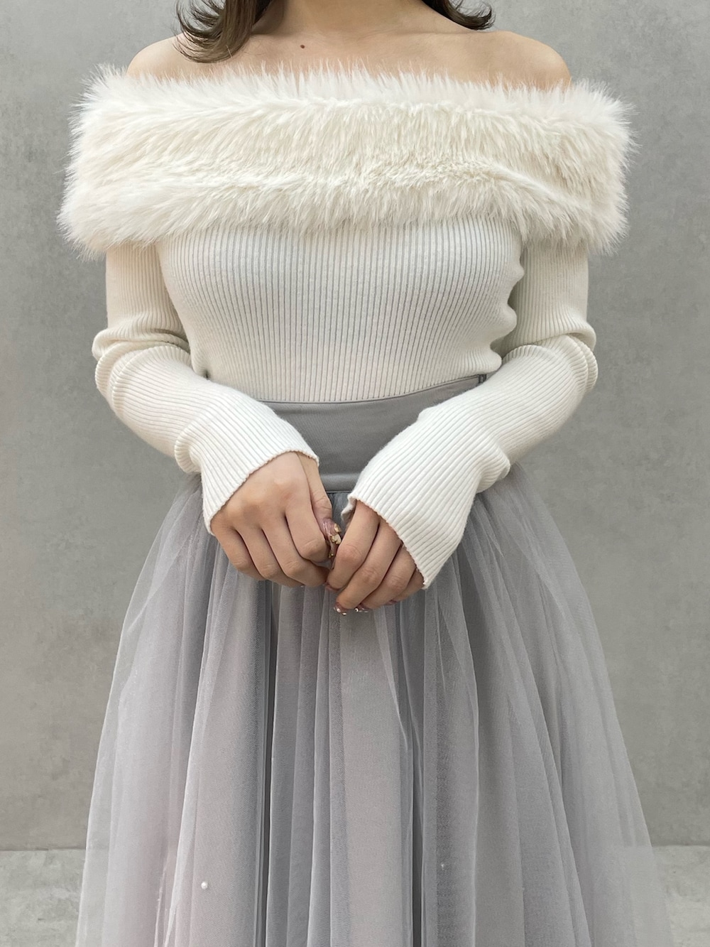 ホワイト系のニット/セーター、グレー系のスカート、ブラック系のブーツを着用したレディースの冬コーディネートの5枚目の写真