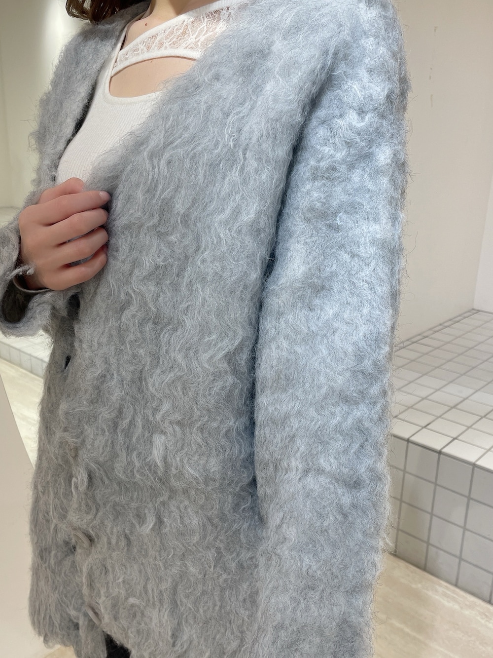 グレー系のカーディガン/ボレロ、ホワイト系のニット/セーター、ブラック系のデニムパンツを着用したレディースの冬コーディネートの9枚目の写真