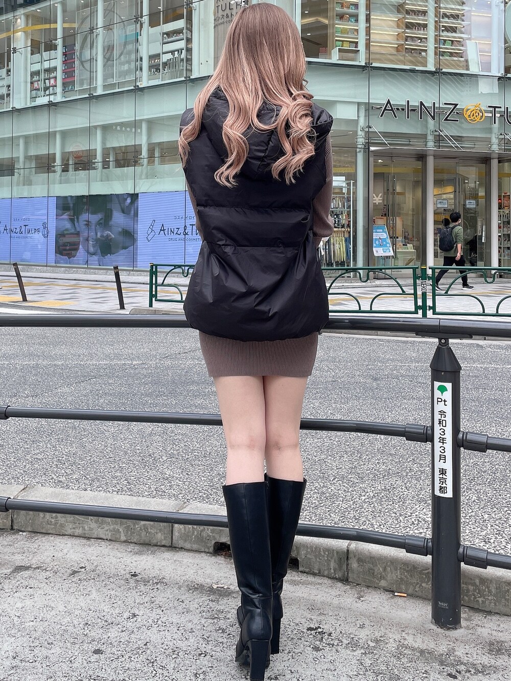 ブラック系のブーツ、ベージュ系のワンピース、ブラック系のダウンベストを着用したレディースの秋コーディネートの3枚目の写真