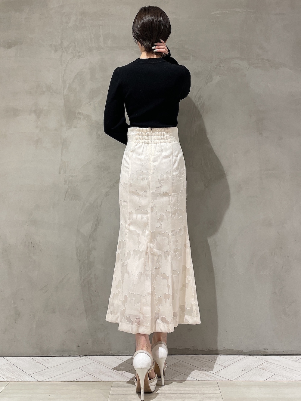 ホワイト系のパンプス、ホワイト系のスカート、ブラック系のニット/セーターを着用したレディースの冬コーディネートの3枚目の写真