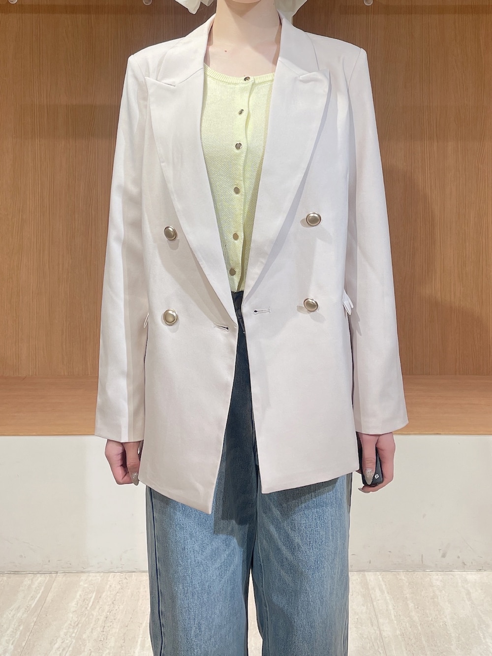 ホワイト系のテーラードジャケット、イエロー系のカーディガン/ボレロ、ブルー系のデニムパンツを着用したレディースの春コーディネートの7枚目の写真