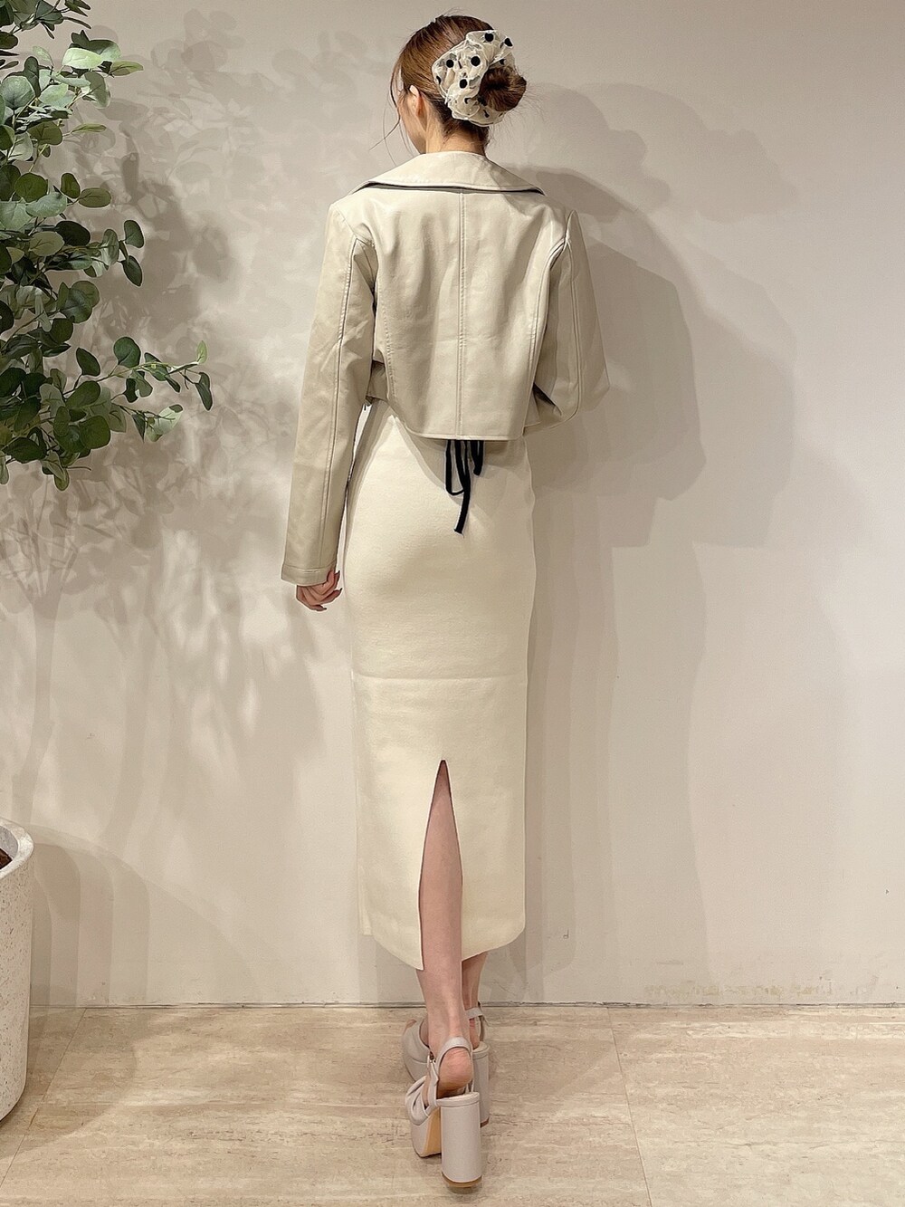 ホワイト系のライダースジャケット、ホワイト系のワンピース、ベージュ系のサンダルを着用したレディースの春コーディネートの3枚目の写真