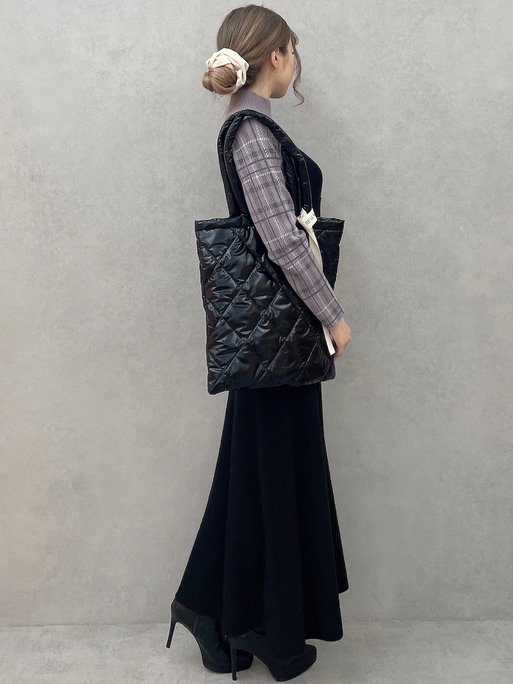 パープル系のニット/セーター、ブラック系のブーツ、ブラック系のジャンパースカートを着用したレディースの秋コーディネートの3枚目の写真