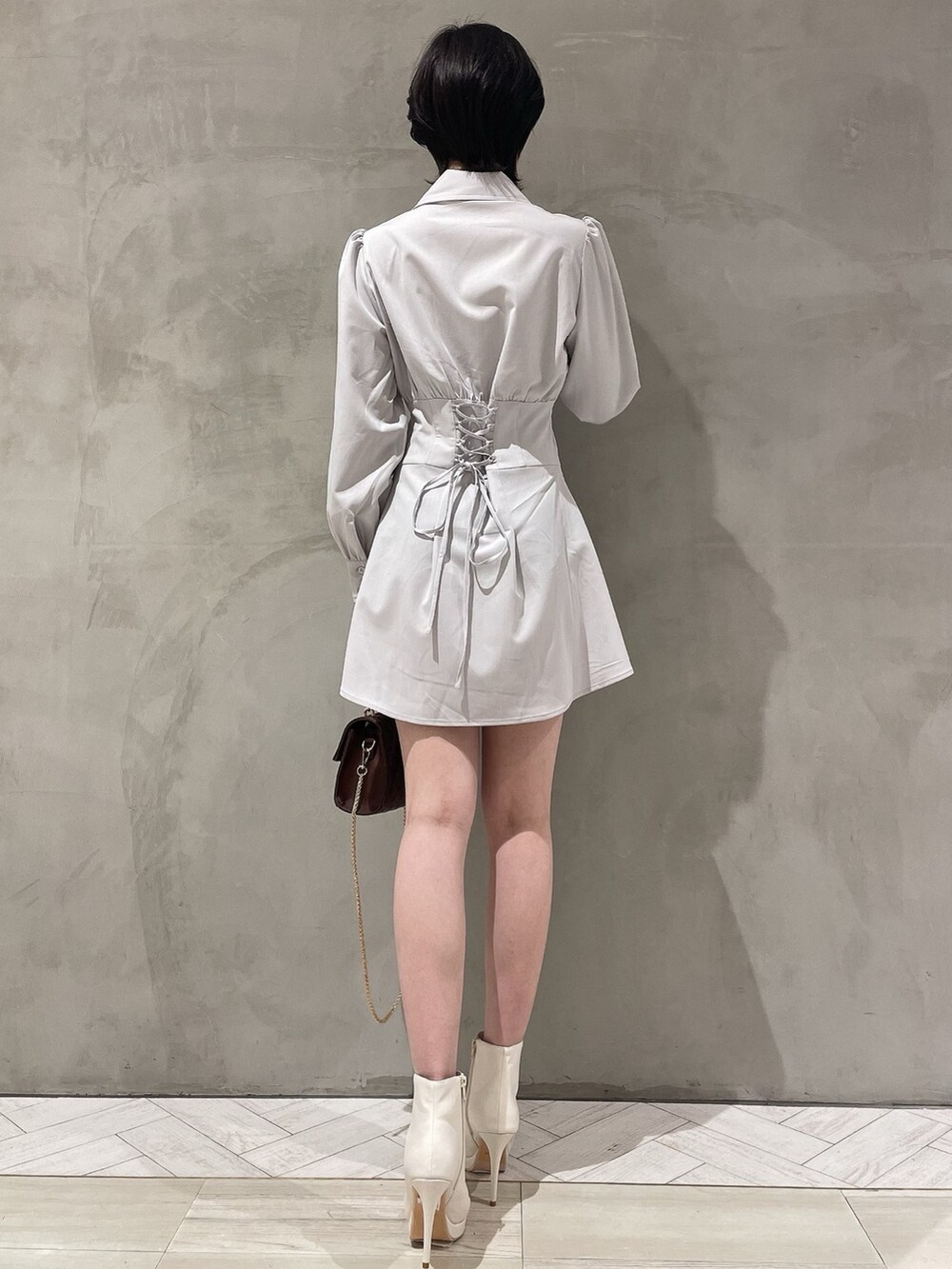 ブラウン系のハンドバッグ、ホワイト系のブーツ、グレー系のシャツワンピースを着用したレディースの冬コーディネートの3枚目の写真