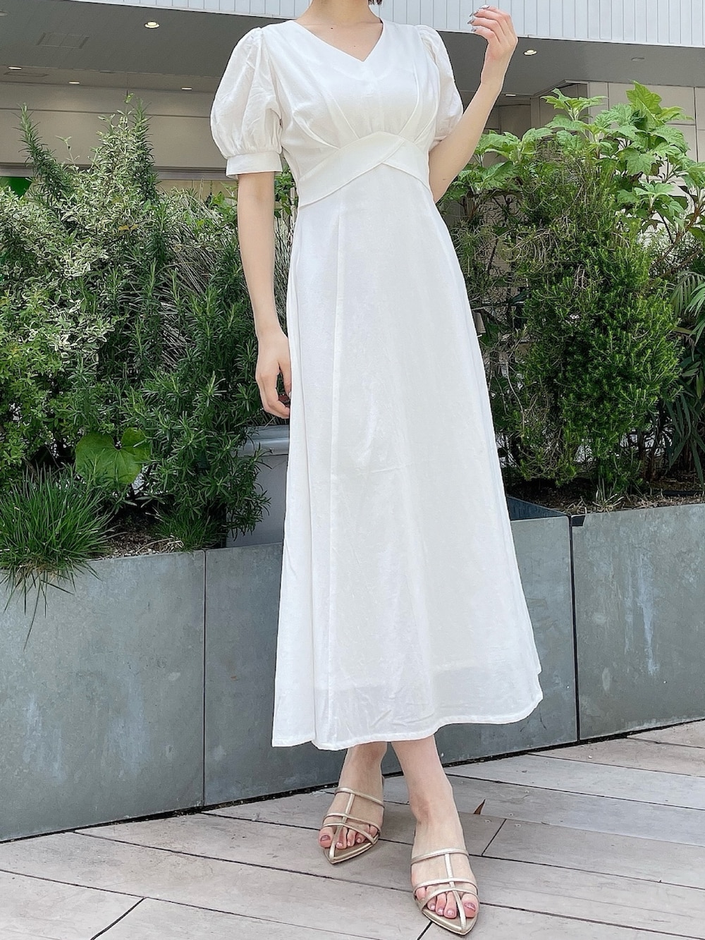 ホワイト系のワンピース、ブルー系のデニムジャケット、ゴールド系のサンダルを着用したレディースの春コーディネートの6枚目の写真