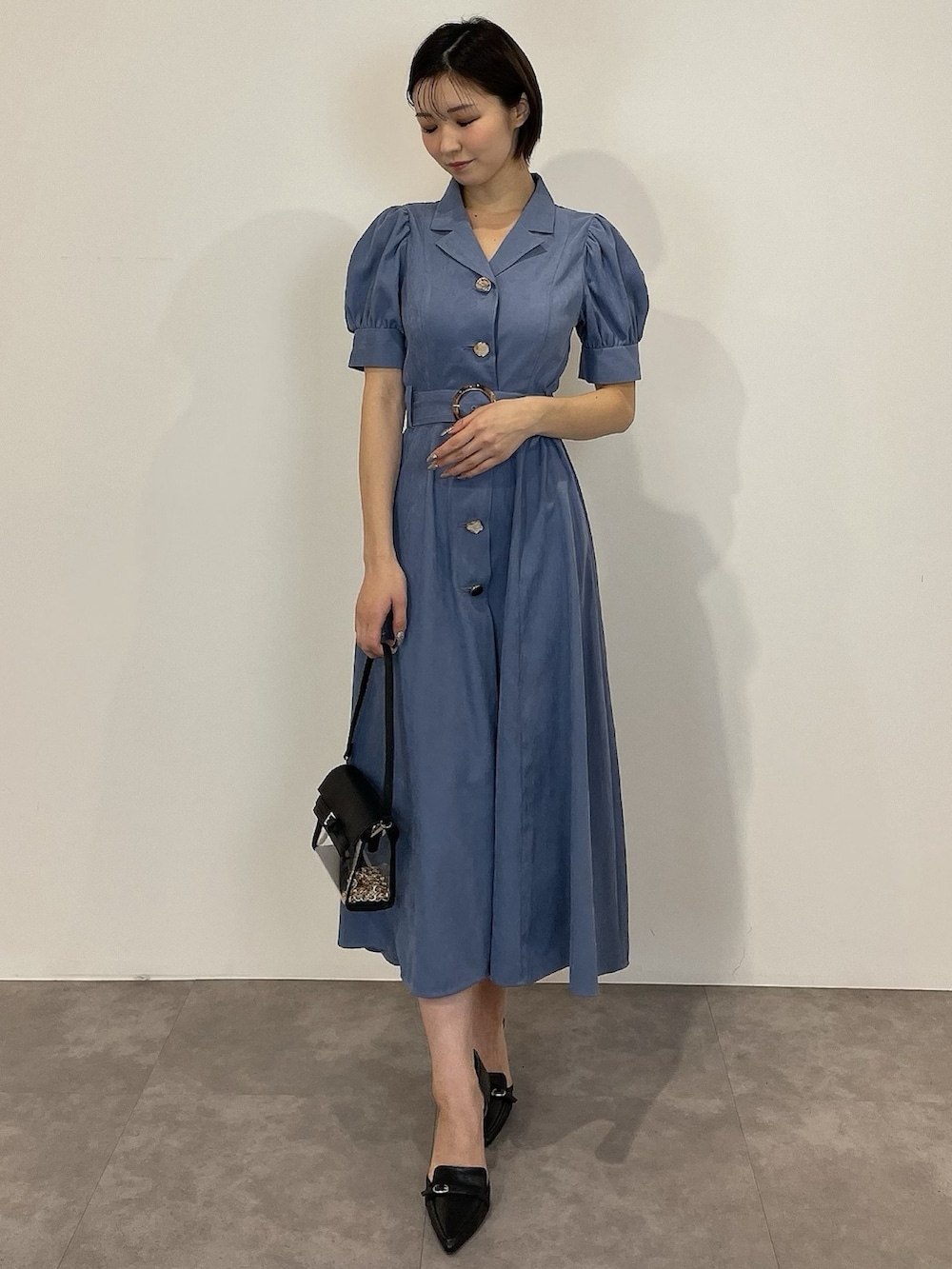 ブルー系のワンピース、ブラック系のパンプス、ブラック系のハンドバッグを着用したレディースの冬コーディネートの3枚目の写真