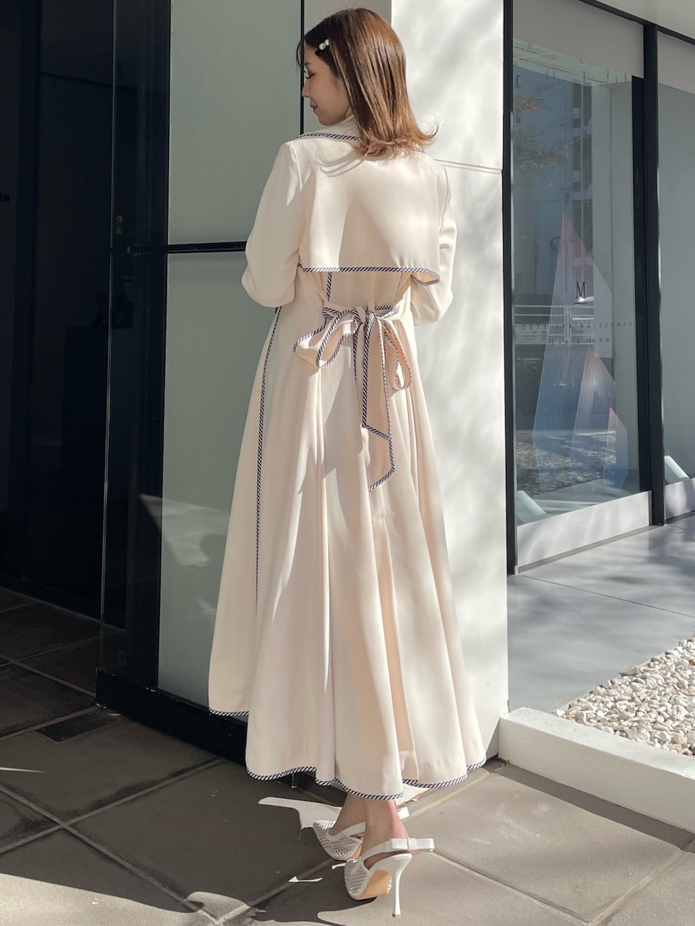 ホワイト系のトレンチコート、ブルー系のワンピース、ホワイト系のパンプスを着用したレディースの冬コーディネートの8枚目の写真