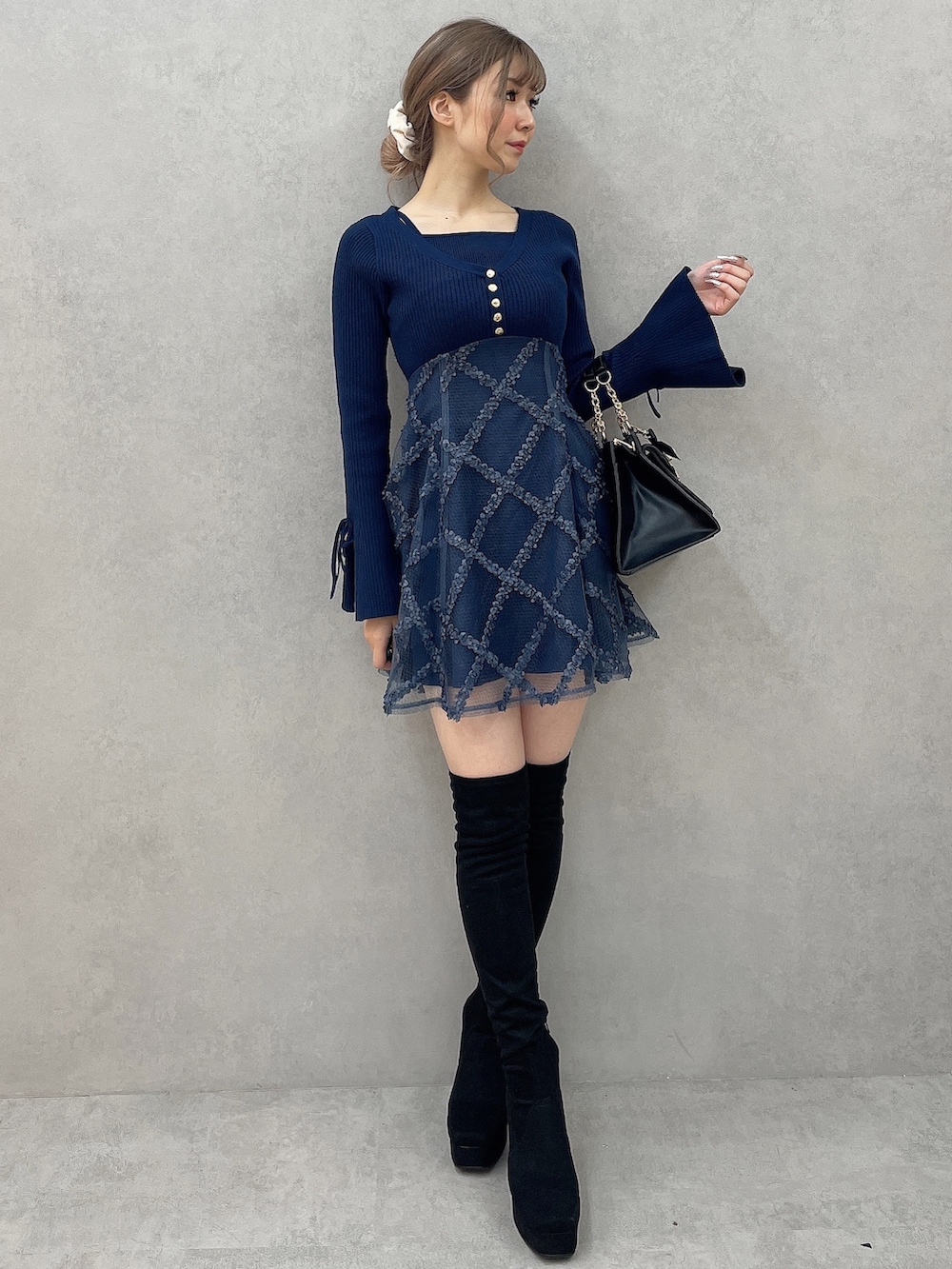 ブルー系のワンピース、ブラック系のハンドバッグ、ブラック系のブーツを着用したレディースの秋コーディネートの2枚目の写真