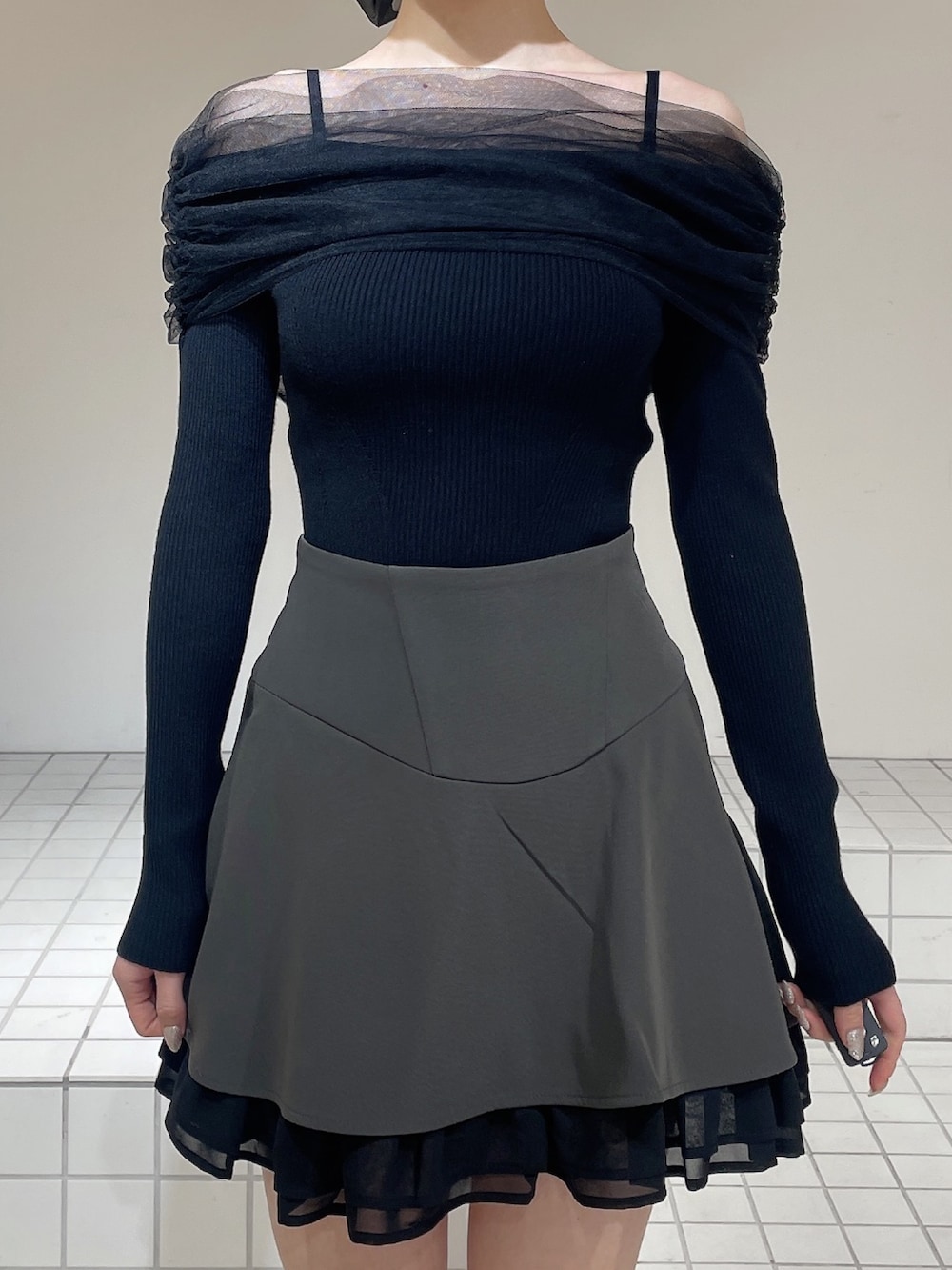 グレー系のスカート、ブラック系のニット/セーター、ブラック系のブーツを着用したレディースの春コーディネートの4枚目の写真