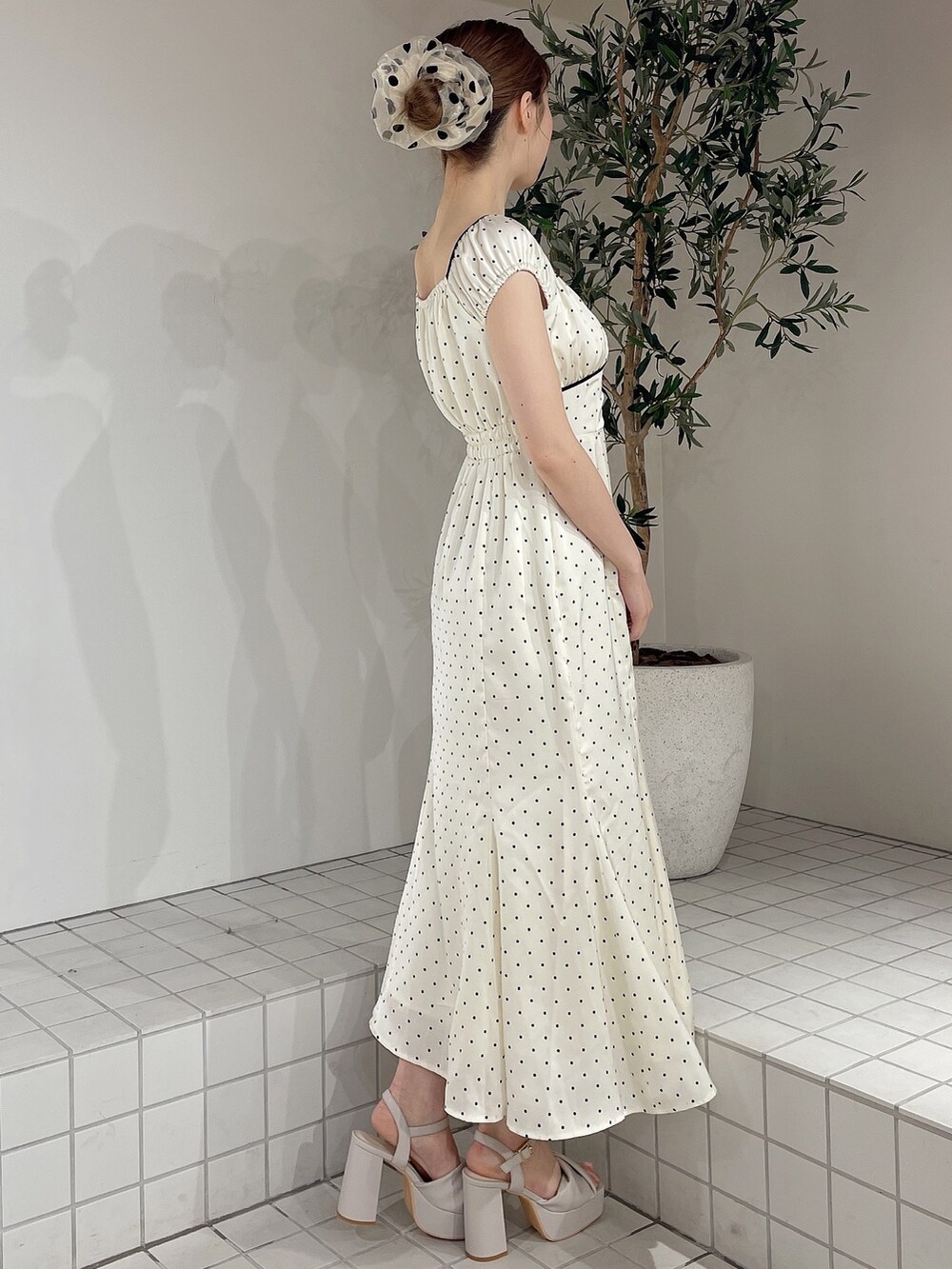 ホワイト系のワンピース、ベージュ系のサンダル、ベージュ系のシュシュを着用したレディースの春コーディネートの2枚目の写真