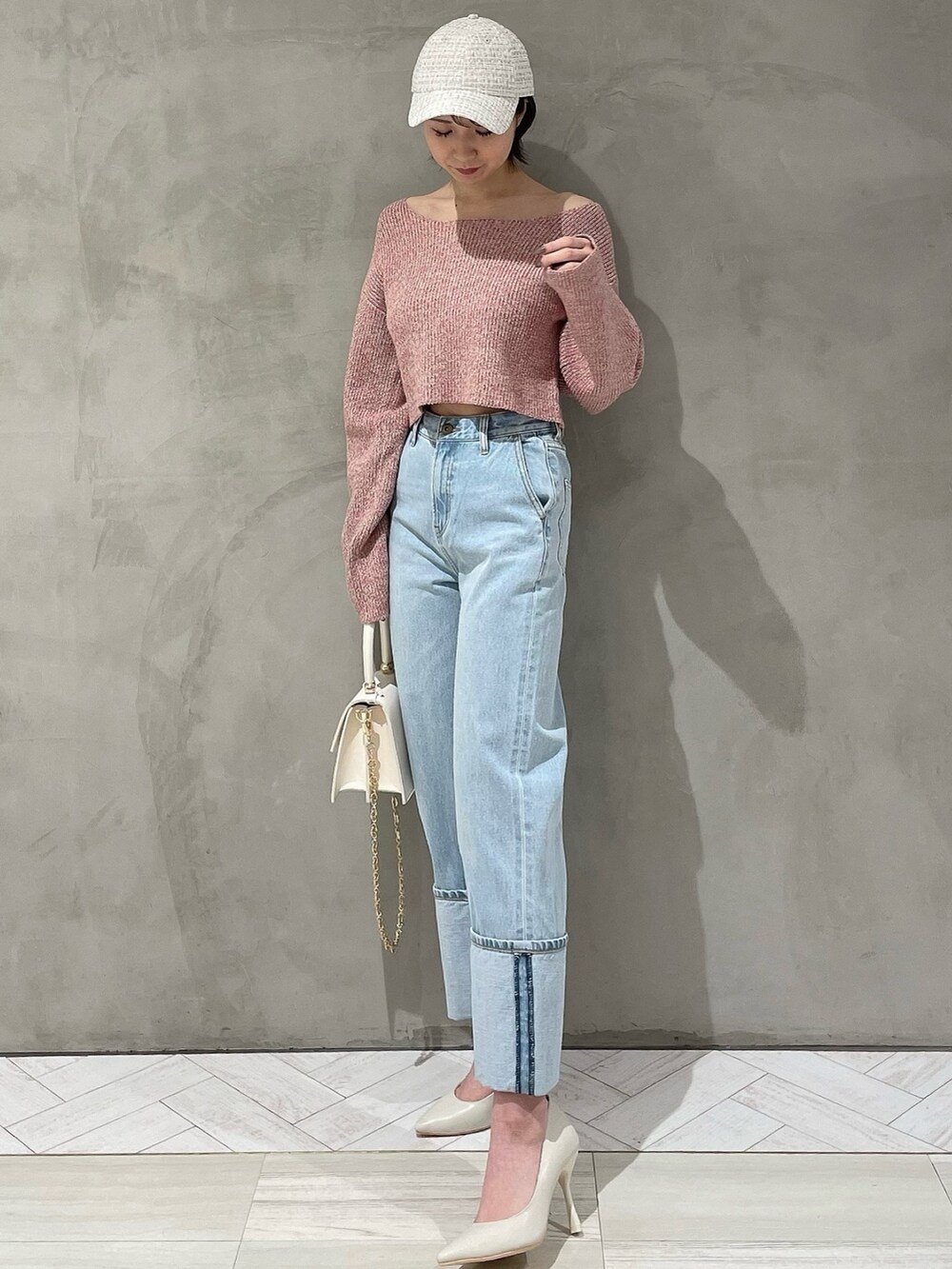 ピンク系のニット/セーター、ホワイト系のハンドバッグ、ブルー系のデニムパンツを着用したレディースの冬コーディネートの2枚目の写真