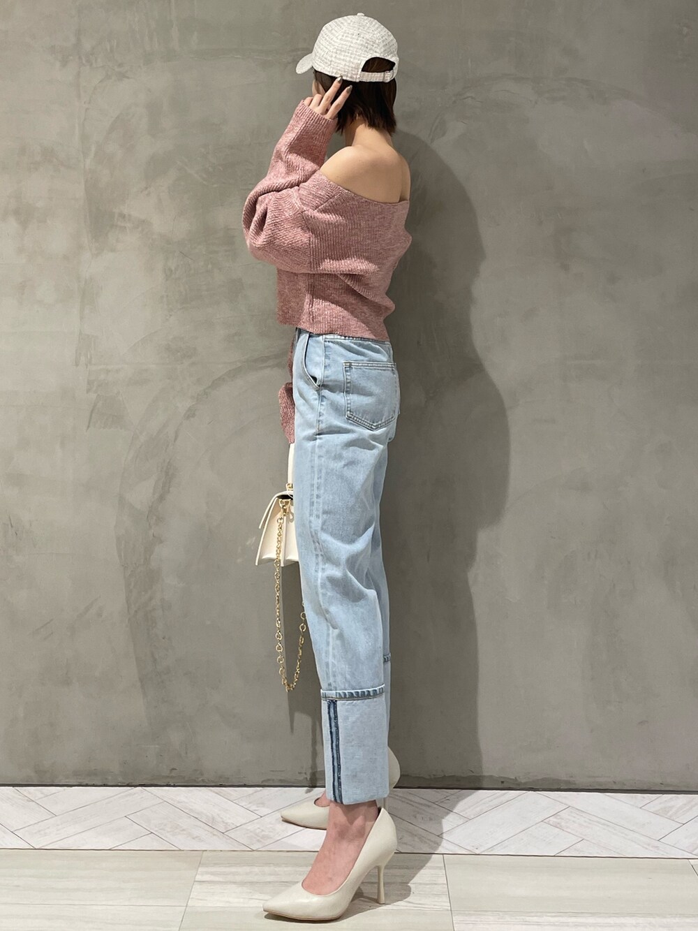 ピンク系のニット/セーター、ホワイト系のハンドバッグ、ブルー系のデニムパンツを着用したレディースの冬コーディネートの3枚目の写真