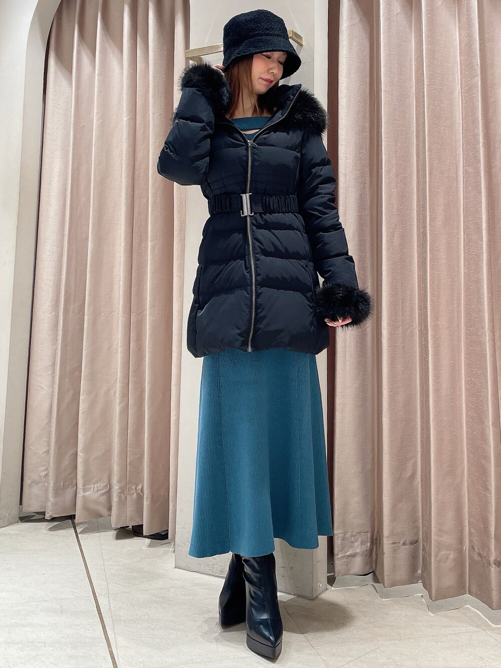 ブルー系のワンピース、ブラック系のブーツ、ブラック系のハットを着用したレディースの冬コーディネートの4枚目の写真