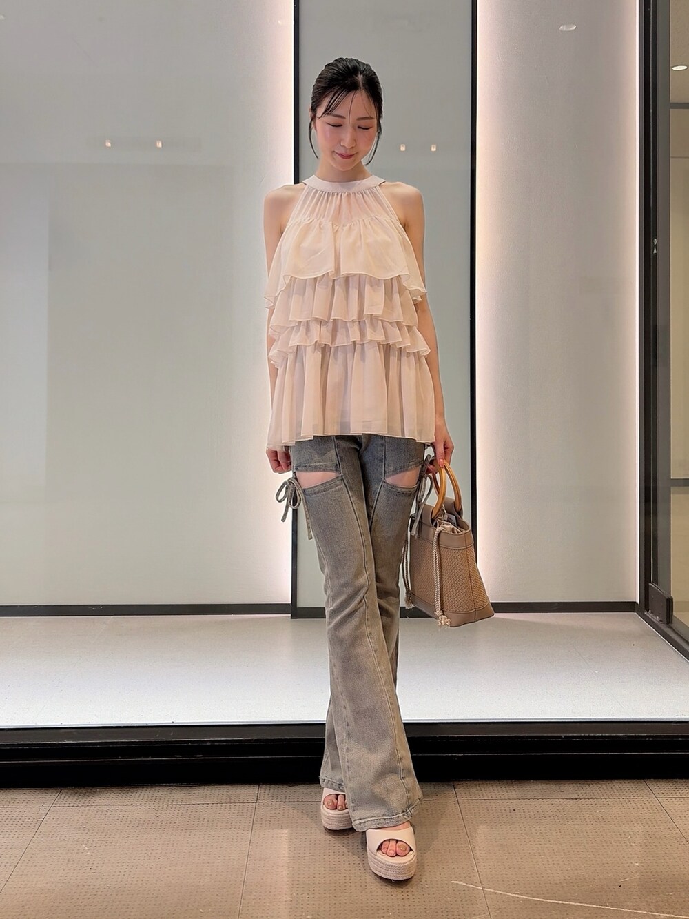 ホワイト系のシャツ/ブラウス、ブルー系のデニムパンツ、ベージュ系のハンドバッグを着用したレディースの夏コーディネートの2枚目の写真