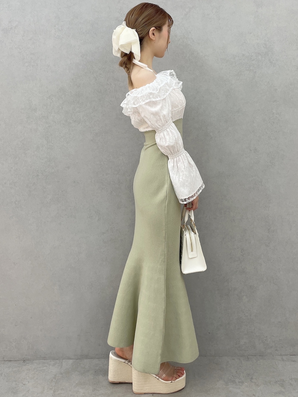 グリーン系のワンピース、ホワイト系のハンドバッグ、ホワイト系のサンダルを着用したレディースの春コーディネートの3枚目の写真