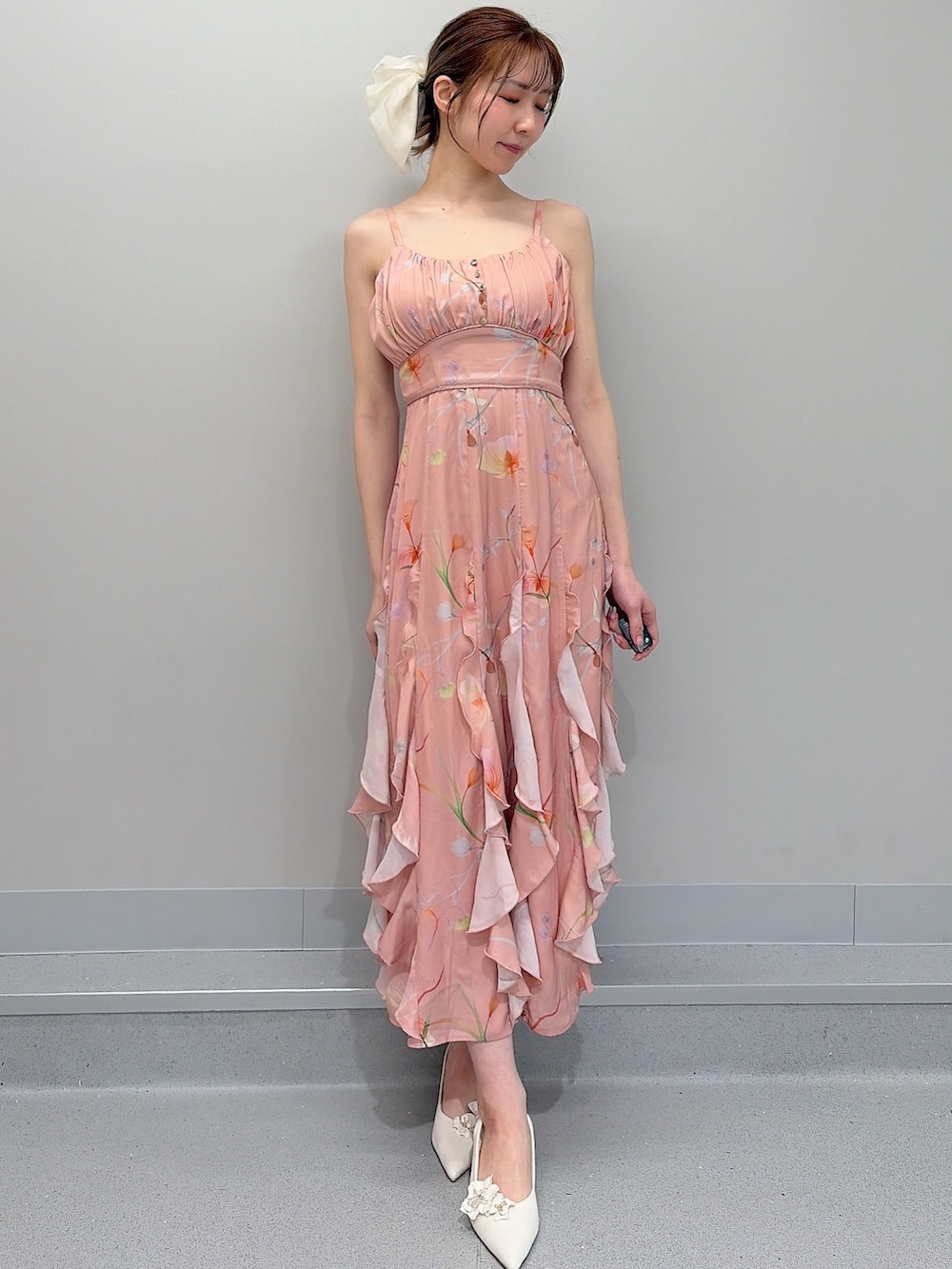 ホワイト系のパンプス、オレンジ系のワンピース、ホワイト系のバレッタ/ヘアクリップを着用したレディースの冬コーディネートの6枚目の写真