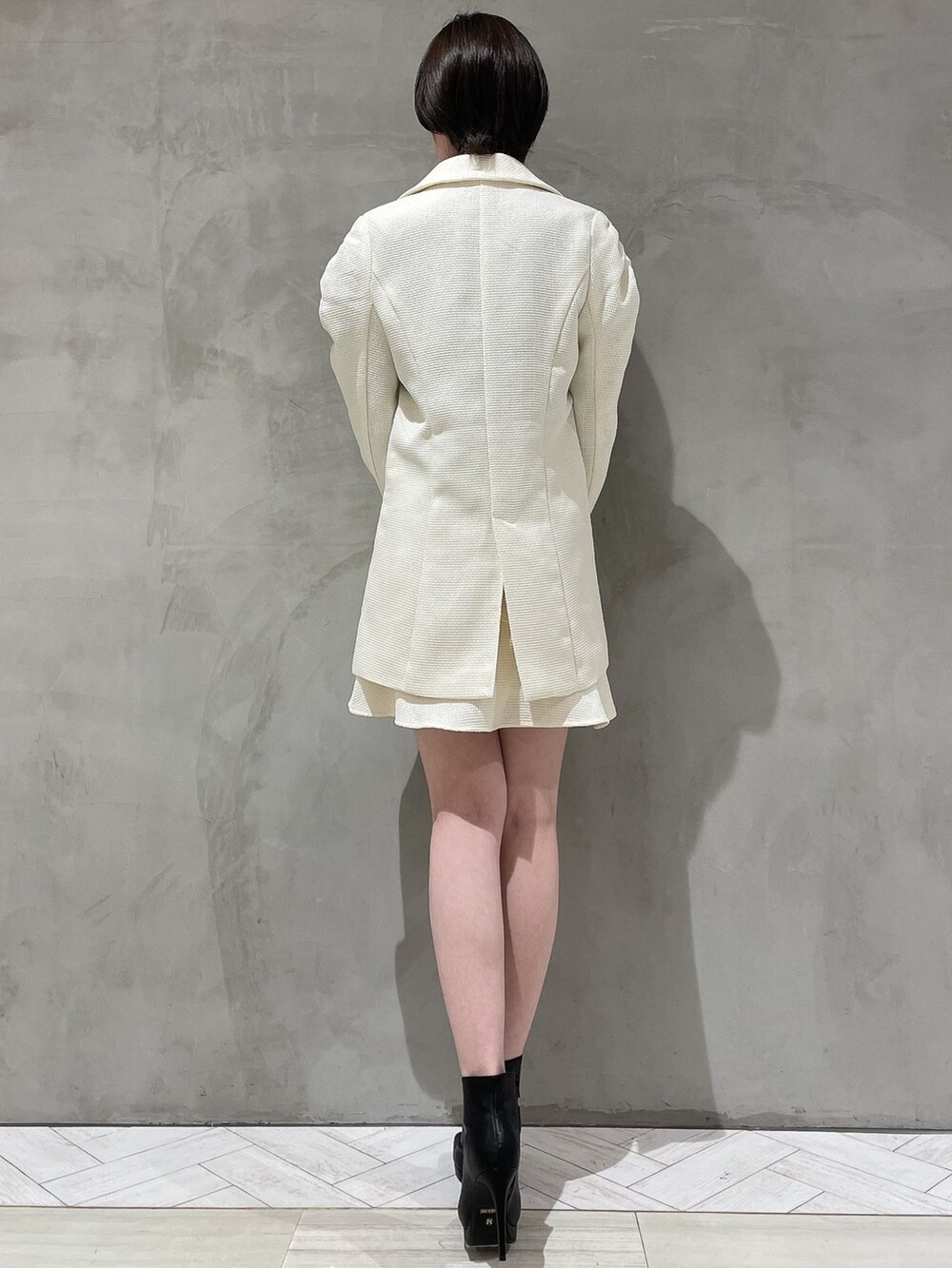 ホワイト系のテーラードジャケット、ホワイト系のスカート、ブラック系のニット/セーターを着用したレディースの冬コーディネートの3枚目の写真