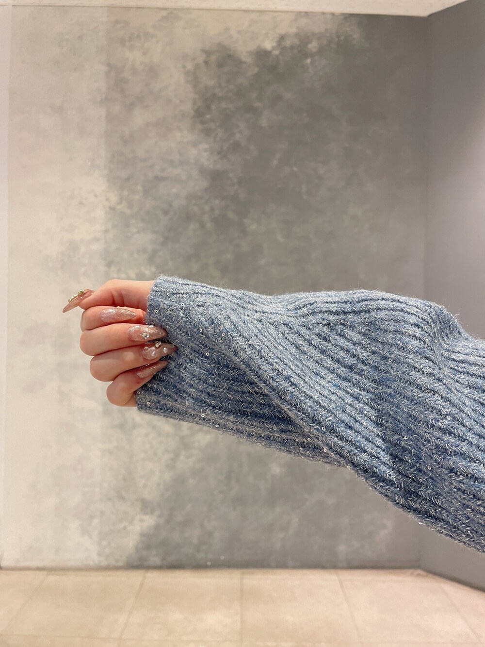 ブルー系のニット/セーター、ブルー系のスカート、ブラック系のブーツを着用したレディースの秋コーディネートの7枚目の写真