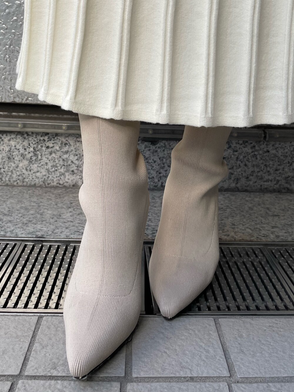 ホワイト系のブーツ、ホワイト系のハンドバッグ、ブルー系のニット/セーターを着用したレディースの冬コーディネートの8枚目の写真