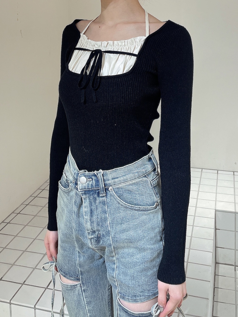 ブラック系のニット/セーター、ブルー系のデニムパンツ、ホワイト系のブーツを着用したレディースの冬コーディネートの5枚目の写真