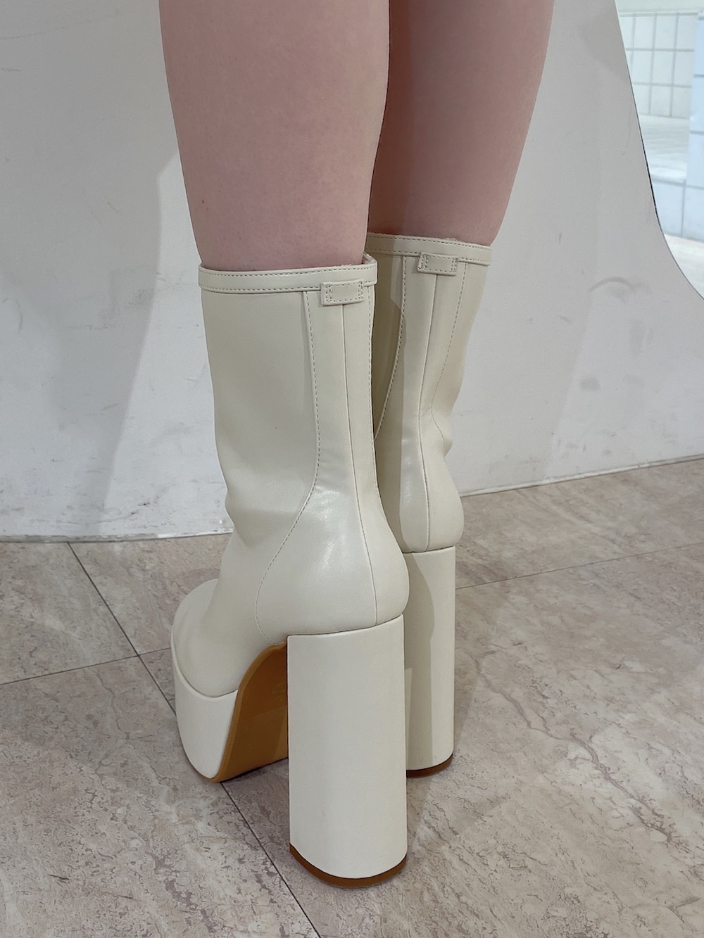 ホワイト系のニット/セーター、ホワイト系のスカート、ホワイト系のブーツを着用したレディースの冬コーディネートの8枚目の写真