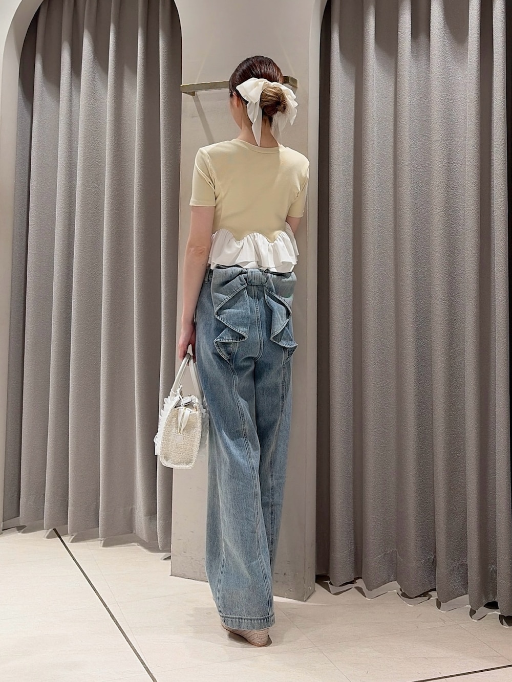 イエロー系のカーディガン/ボレロ、ホワイト系のトートバッグ、ブルー系のデニムパンツを着用したレディースの夏コーディネートの3枚目の写真